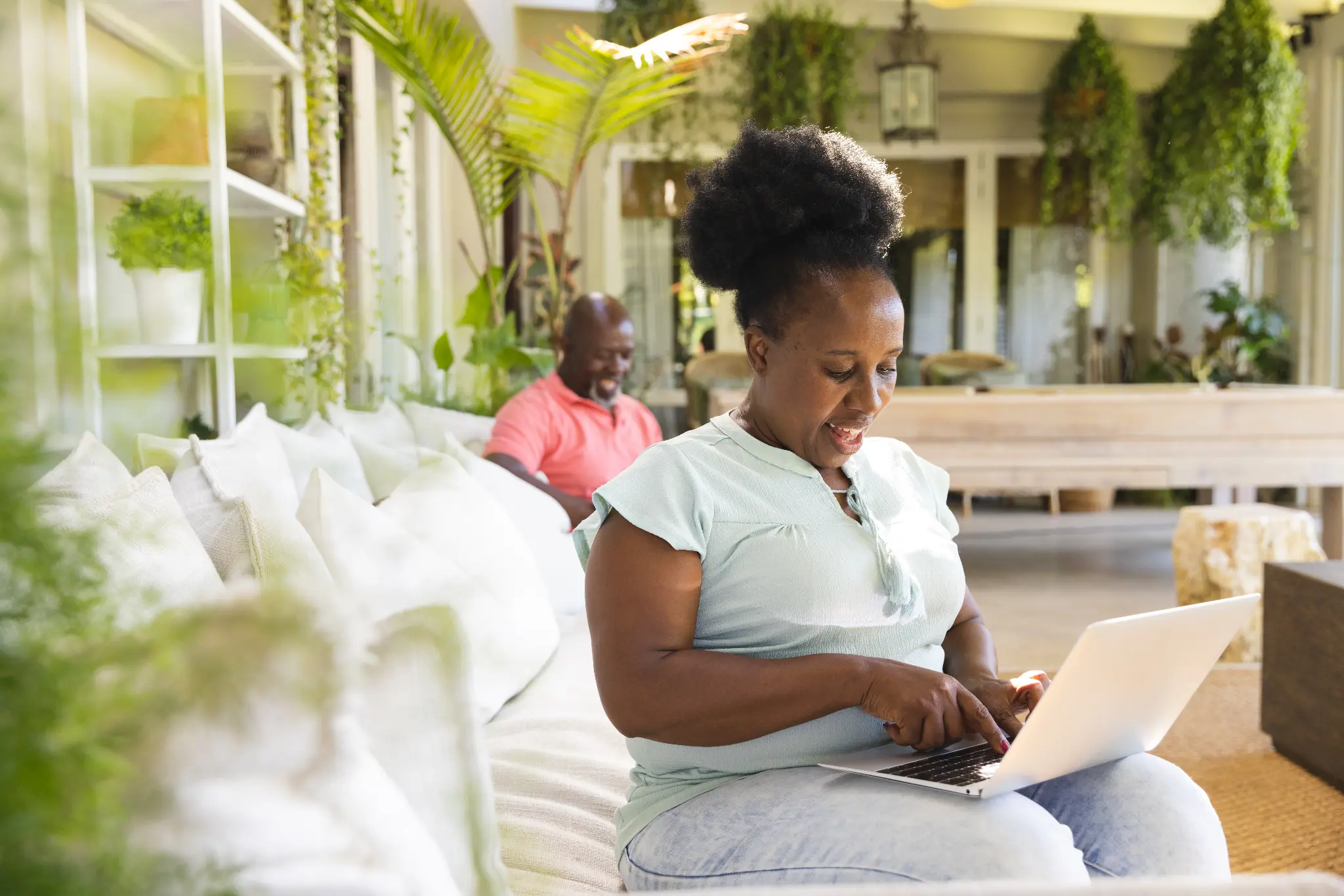 Woman working on a laptop in a bright, plant-filled home